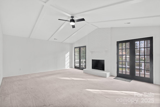 unfurnished living room with french doors, lofted ceiling with beams, ceiling fan, a fireplace, and light colored carpet