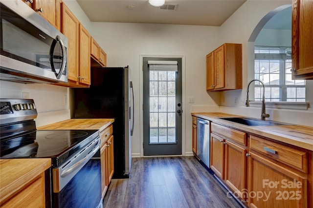 kitchen featuring dark hardwood / wood-style floors, sink, stainless steel appliances, and a wealth of natural light