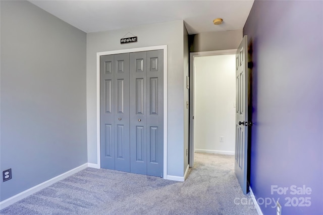 unfurnished bedroom featuring a closet and light colored carpet