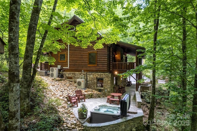 rear view of property with ac unit, a patio, and a hot tub