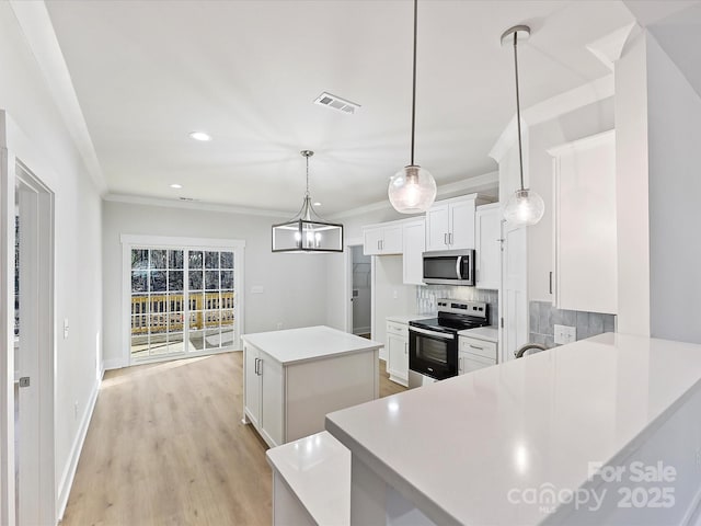 kitchen with pendant lighting, a kitchen island, decorative backsplash, white cabinetry, and appliances with stainless steel finishes