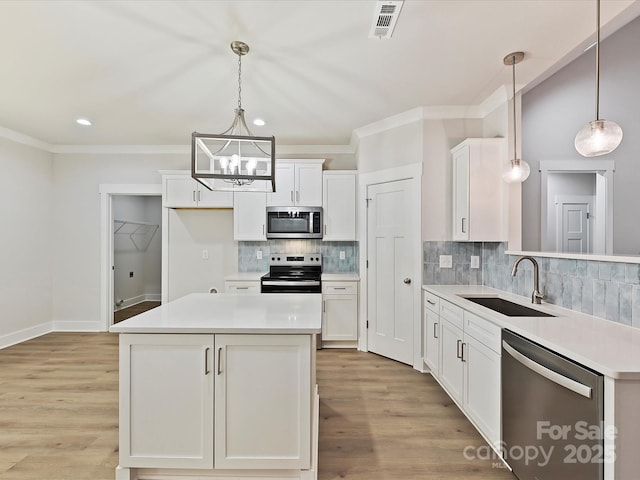 kitchen with sink, hanging light fixtures, white cabinets, and stainless steel appliances