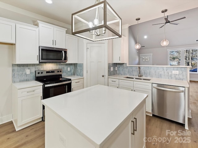 kitchen featuring white cabinetry, stainless steel appliances, a kitchen island, pendant lighting, and sink