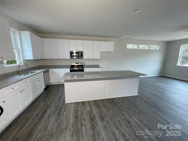 kitchen featuring white cabinetry, sink, a center island, light stone countertops, and appliances with stainless steel finishes