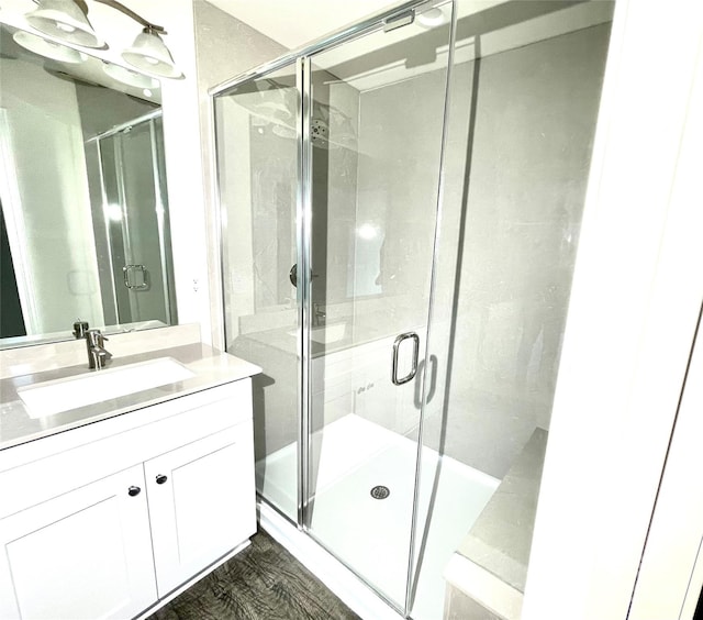 bathroom with vanity, hardwood / wood-style flooring, and a shower with door