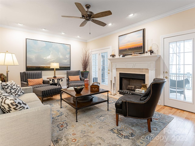 living room with ceiling fan, a fireplace, hardwood / wood-style floors, and ornamental molding