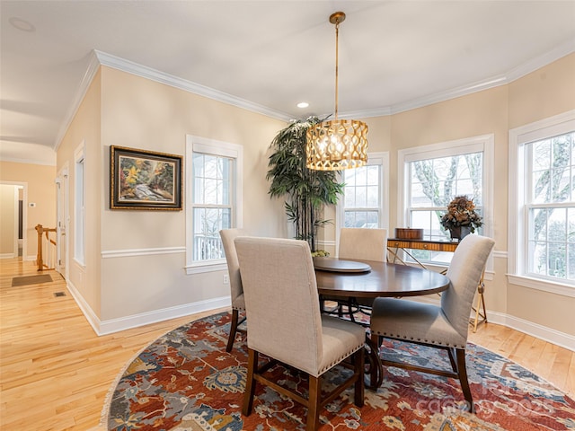 dining area featuring light hardwood / wood-style floors, ornamental molding, and an inviting chandelier