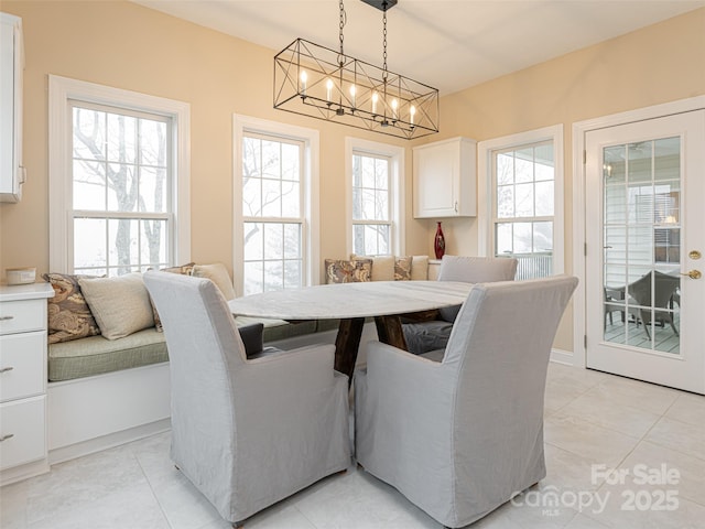 dining room with light tile patterned floors, breakfast area, an inviting chandelier, and a healthy amount of sunlight