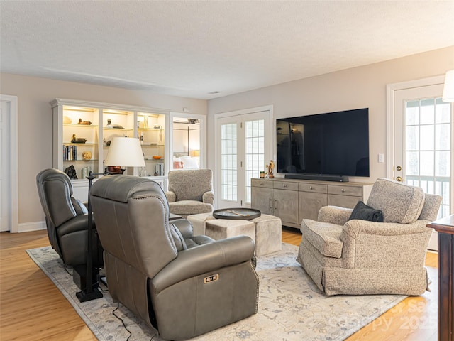 living room featuring french doors, light hardwood / wood-style flooring, and a textured ceiling