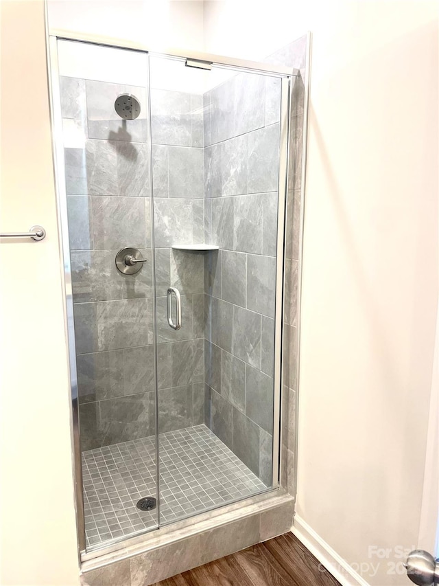 bathroom with hardwood / wood-style flooring and a shower with shower door