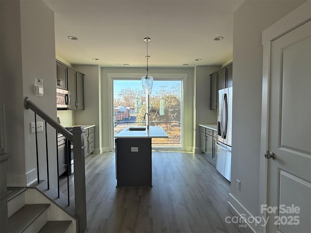 kitchen featuring a kitchen island with sink, an inviting chandelier, decorative light fixtures, dark hardwood / wood-style flooring, and stainless steel appliances