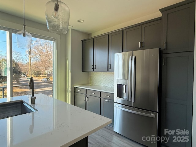 kitchen with backsplash, hanging light fixtures, a notable chandelier, light stone counters, and stainless steel fridge with ice dispenser