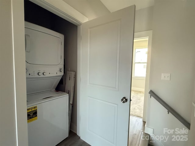 washroom with wood-type flooring and stacked washing maching and dryer