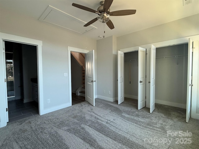 unfurnished bedroom featuring carpet, ceiling fan, connected bathroom, and two closets