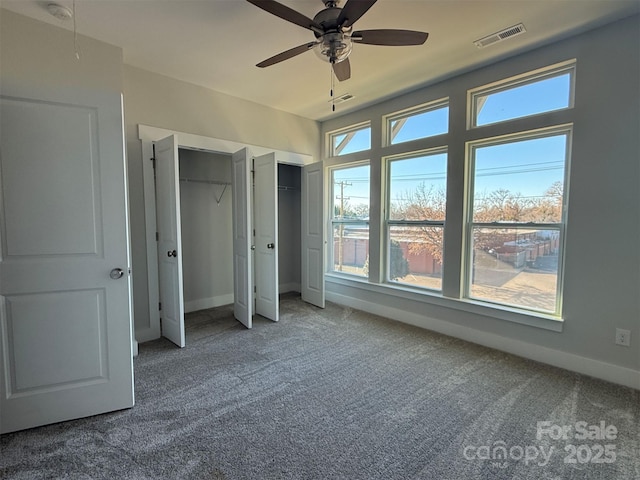 unfurnished bedroom featuring multiple closets, ceiling fan, and carpet