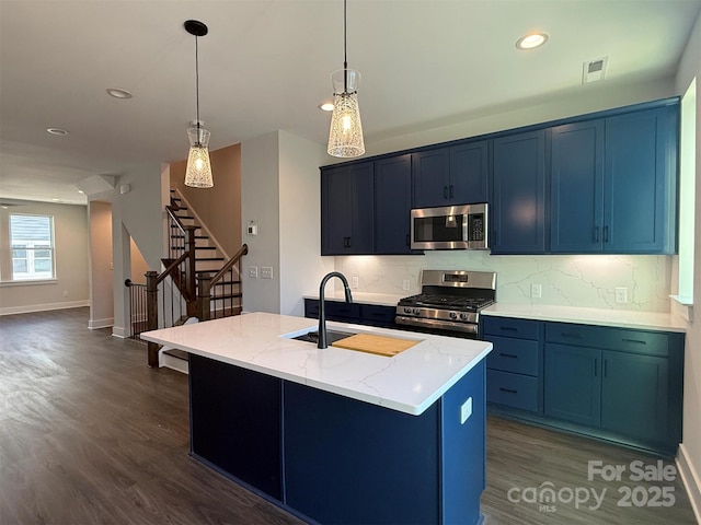 kitchen featuring tasteful backsplash, blue cabinetry, stainless steel appliances, and a sink