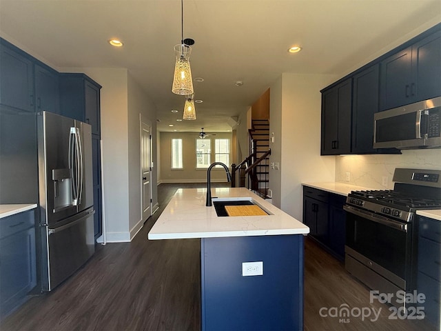 kitchen featuring backsplash, stainless steel appliances, ceiling fan, sink, and an island with sink