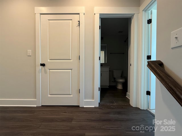 corridor featuring dark wood-type flooring and baseboards