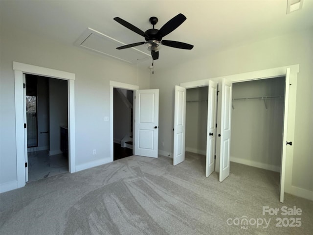 unfurnished bedroom with baseboards, light carpet, two closets, and attic access