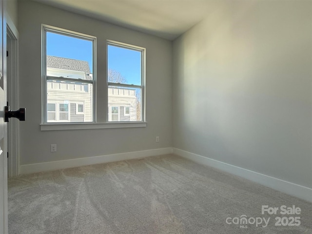 carpeted empty room featuring baseboards