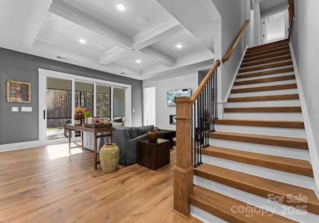 living room with coffered ceiling, a fireplace, beam ceiling, and light hardwood / wood-style floors