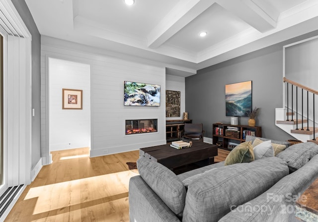 living room with ornamental molding, light wood-type flooring, and beam ceiling