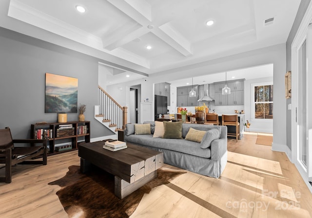 living room with beam ceiling, coffered ceiling, and light wood-type flooring