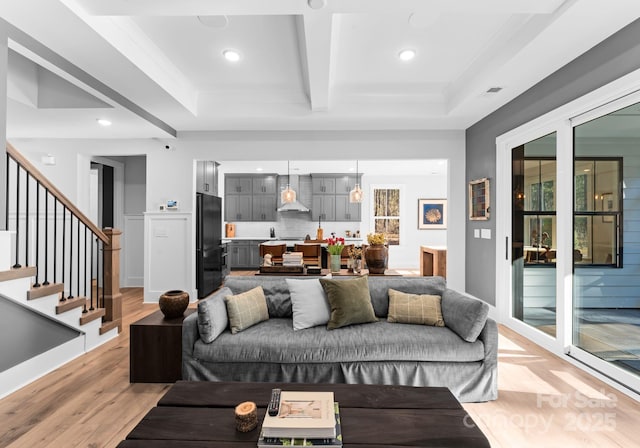 living room featuring beamed ceiling, ornamental molding, coffered ceiling, and light hardwood / wood-style flooring