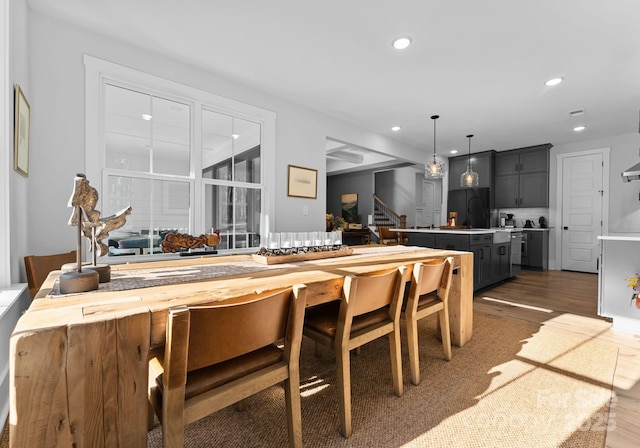 kitchen with butcher block countertops, decorative light fixtures, a kitchen breakfast bar, dark hardwood / wood-style flooring, and black built in fridge