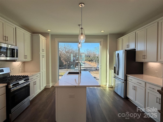 kitchen with sink, stainless steel appliances, pendant lighting, a kitchen island with sink, and white cabinets