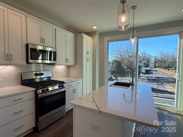 kitchen featuring hanging light fixtures, sink, stainless steel appliances, and a kitchen island with sink