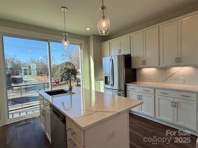 kitchen with sink, hanging light fixtures, an island with sink, white cabinetry, and stainless steel appliances