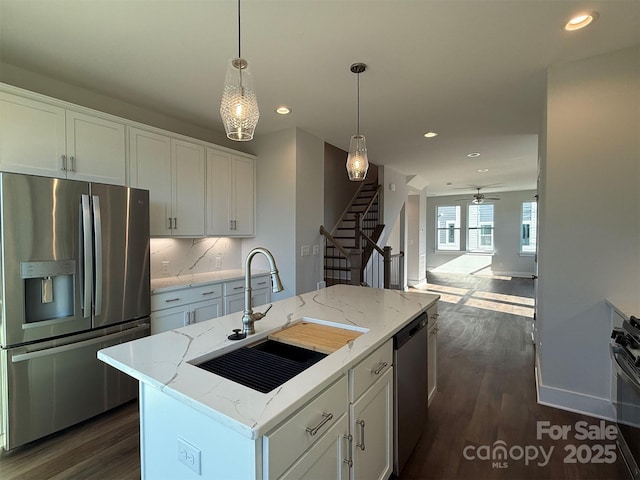 kitchen featuring stainless steel appliances, a kitchen island with sink, ceiling fan, sink, and white cabinetry