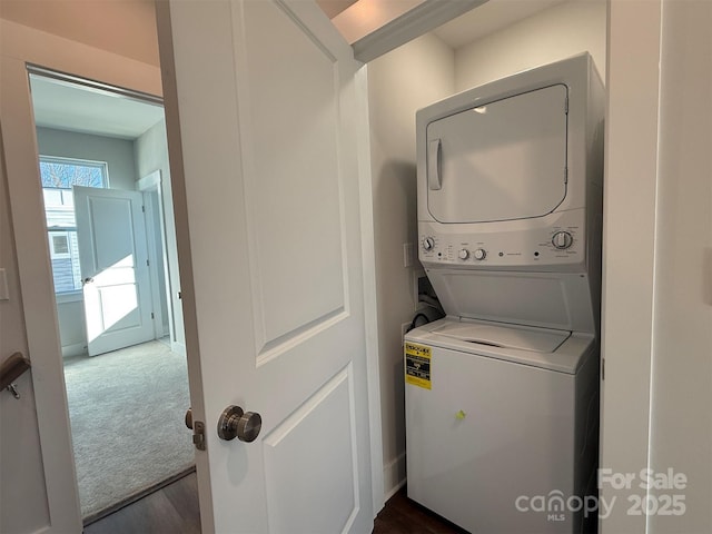 laundry area featuring dark colored carpet and stacked washer / dryer