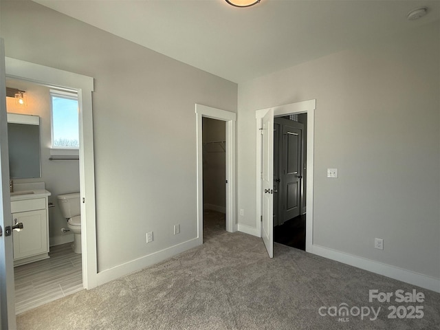 1229 E 34th St Unit Csw0421, Charlotte, NC 28205 - unfurnished bedroom with a spacious closet, baseboards, light colored carpet, connected bathroom, and a closet