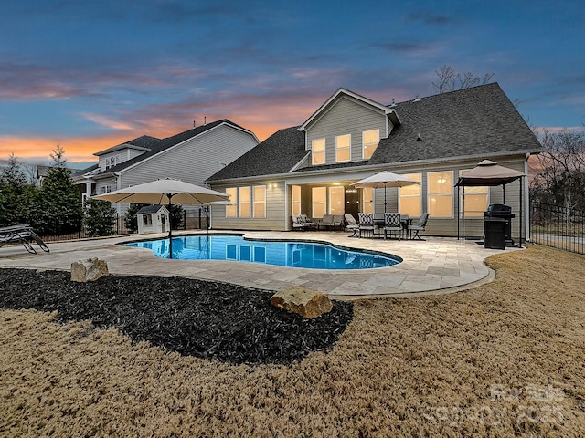 pool at dusk featuring a gazebo, a patio area, a yard, and grilling area