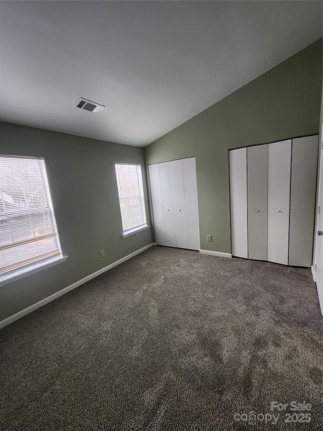 unfurnished bedroom with dark carpet and lofted ceiling