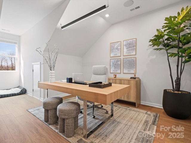 home office with light wood-type flooring, baseboards, visible vents, and vaulted ceiling