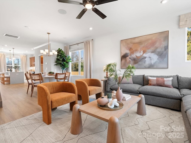 living room with recessed lighting, visible vents, ornamental molding, light wood-style floors, and ceiling fan with notable chandelier