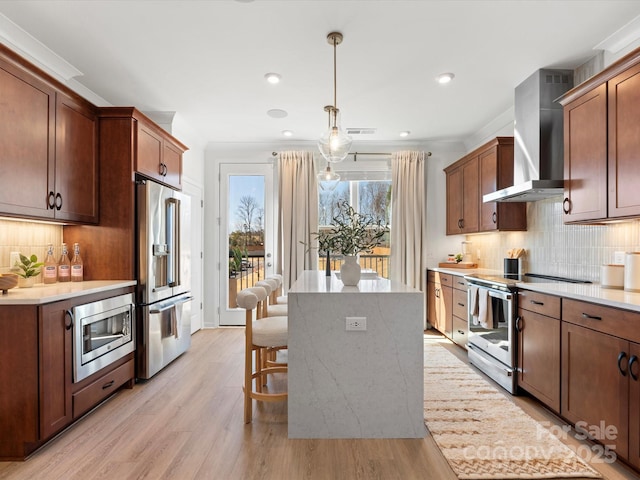 kitchen featuring backsplash, a center island, wall chimney range hood, ornamental molding, and appliances with stainless steel finishes