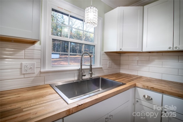 kitchen featuring wood counters, white cabinetry, and hanging light fixtures