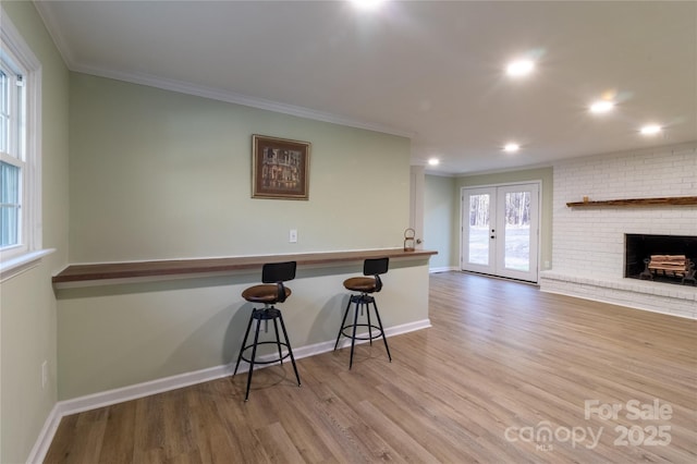 kitchen with a kitchen bar, french doors, hardwood / wood-style flooring, and crown molding