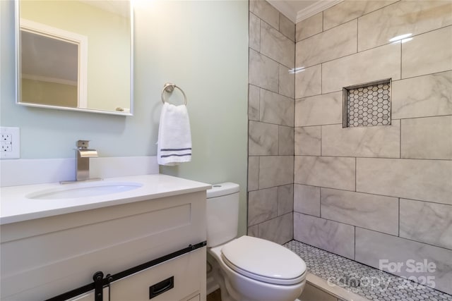 bathroom featuring vanity, toilet, ornamental molding, and tiled shower