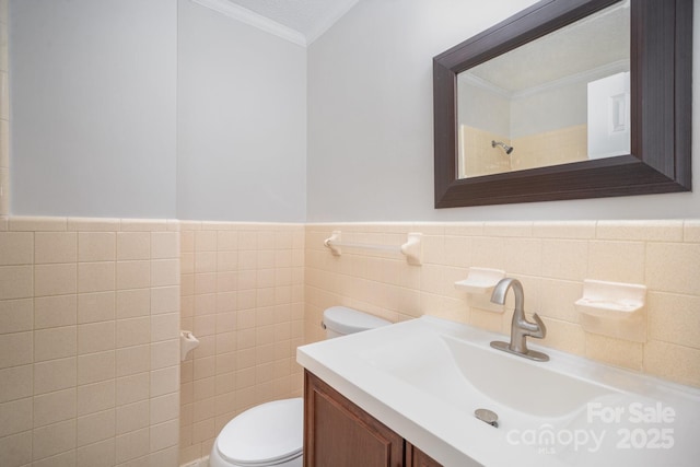 bathroom with vanity, toilet, ornamental molding, and tile walls