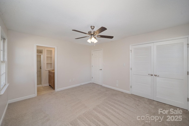 unfurnished bedroom featuring connected bathroom, ceiling fan, a closet, and light colored carpet