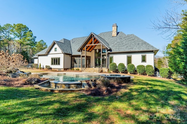 rear view of house with a swimming pool with hot tub and a yard