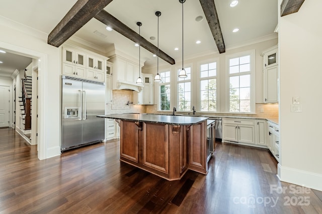 kitchen featuring pendant lighting, white cabinetry, built in refrigerator, a center island, and beamed ceiling