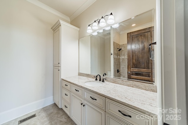 bathroom with crown molding, tiled shower, and vanity