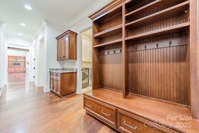 mudroom with ornamental molding, washer and clothes dryer, and light hardwood / wood-style floors