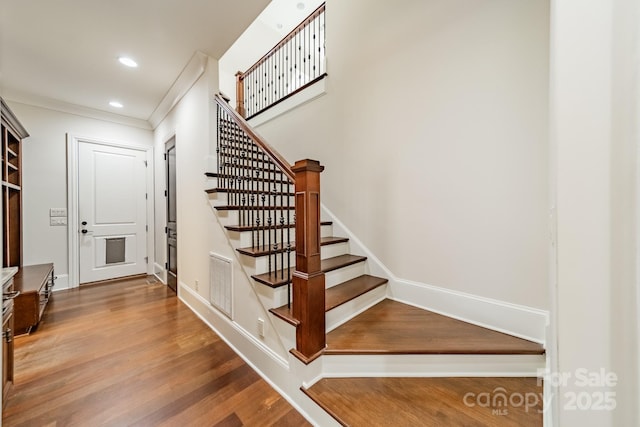 stairs featuring crown molding and wood-type flooring